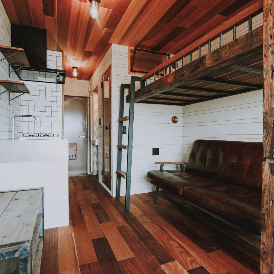 木板貼りの天井とソファとロフトベッドのあるワンルーム